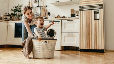 Mor leger med sit barn i en vasketøjskurv på gulvet